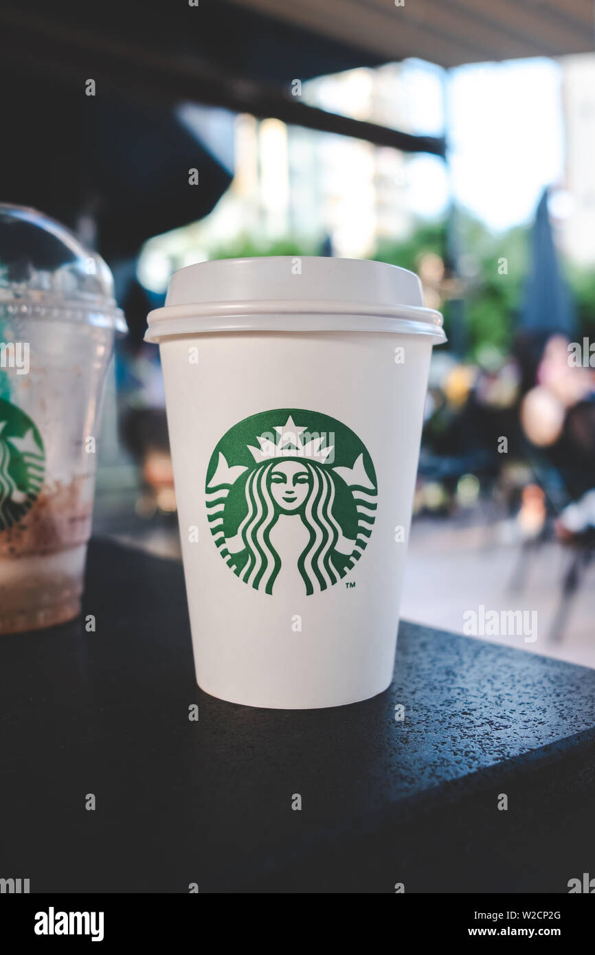 Starbucks beverage and coffee cup on the table with people in the starbucks cafe. Stock Photo