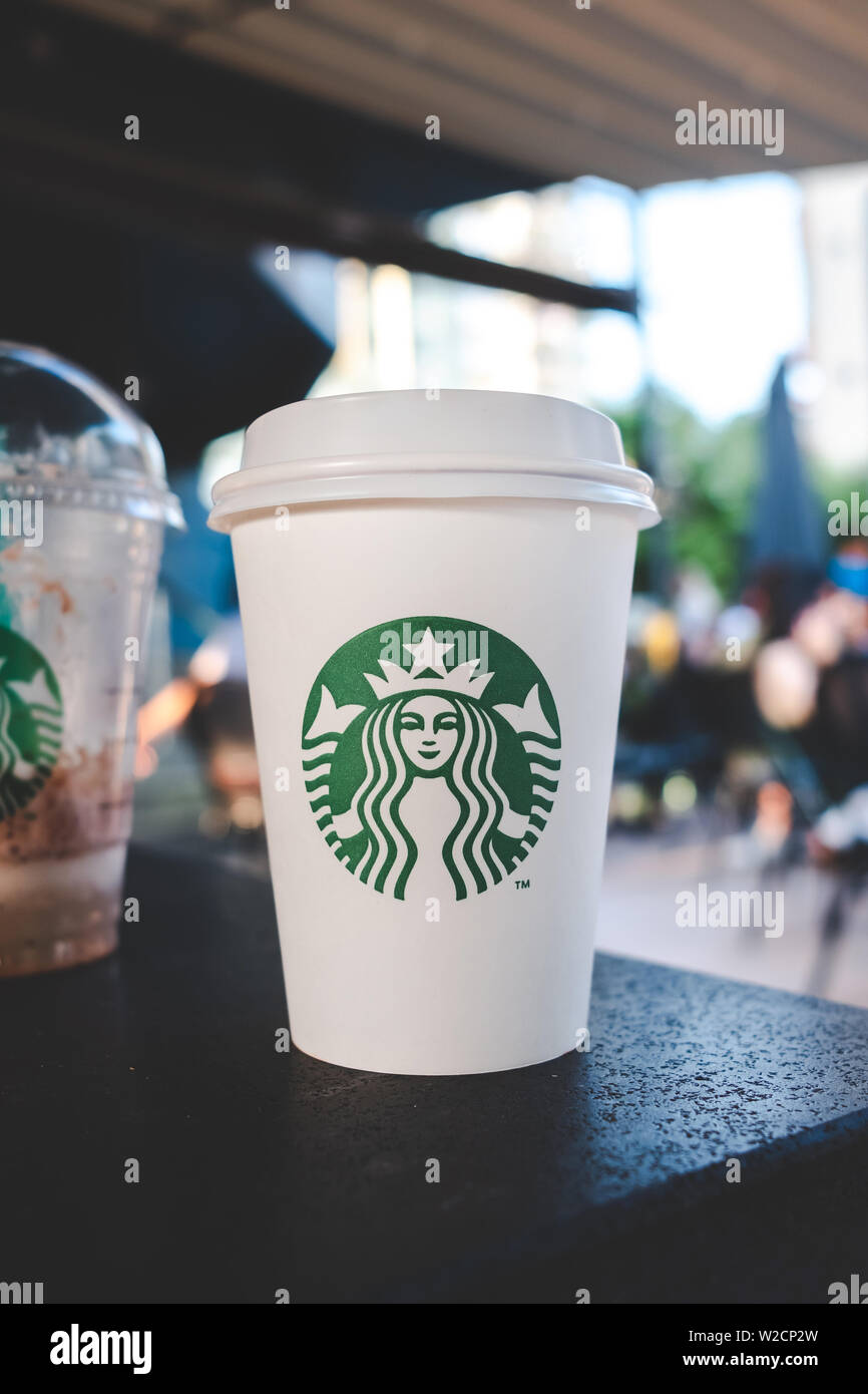 Starbucks beverage and coffee cup on the table with people in the starbucks cafe. Stock Photo