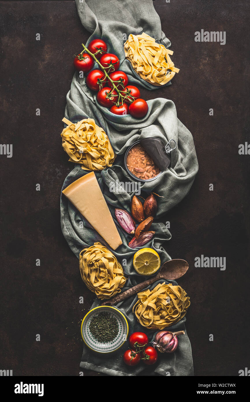 Tuna pasta cooking ingredients on dark rustic background, top view. Grocery products of Italian cuisine. Italian food. Caned tuna. Vertical. Flat lay Stock Photo