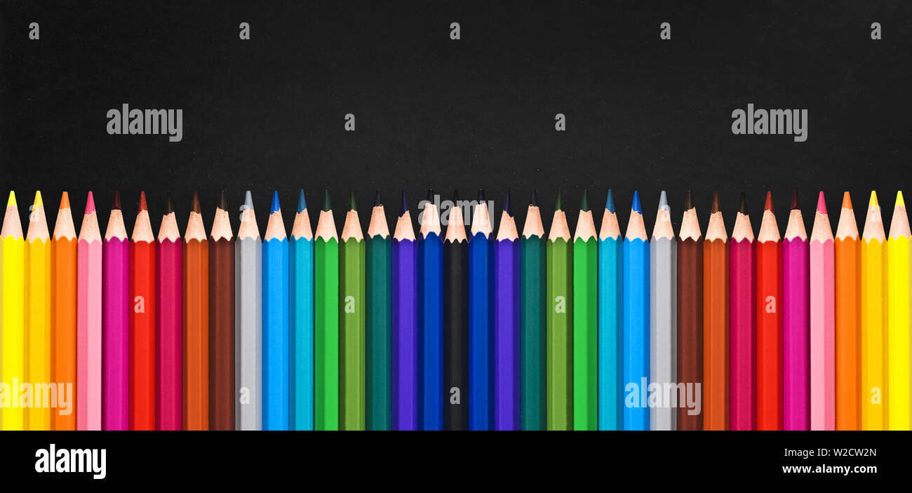 Row of colorful wooden pencils on blackboard background with copy space, back to school concept Stock Photo