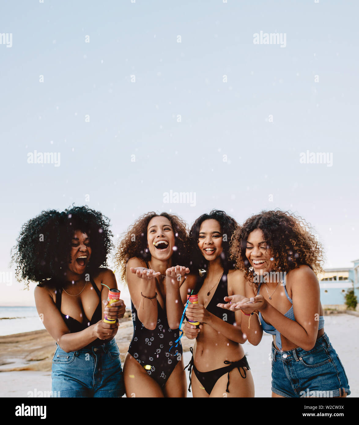 Group of girls in bikini enjoying on the beach. Happy young women playing  confetti at the beach Stock Photo - Alamy