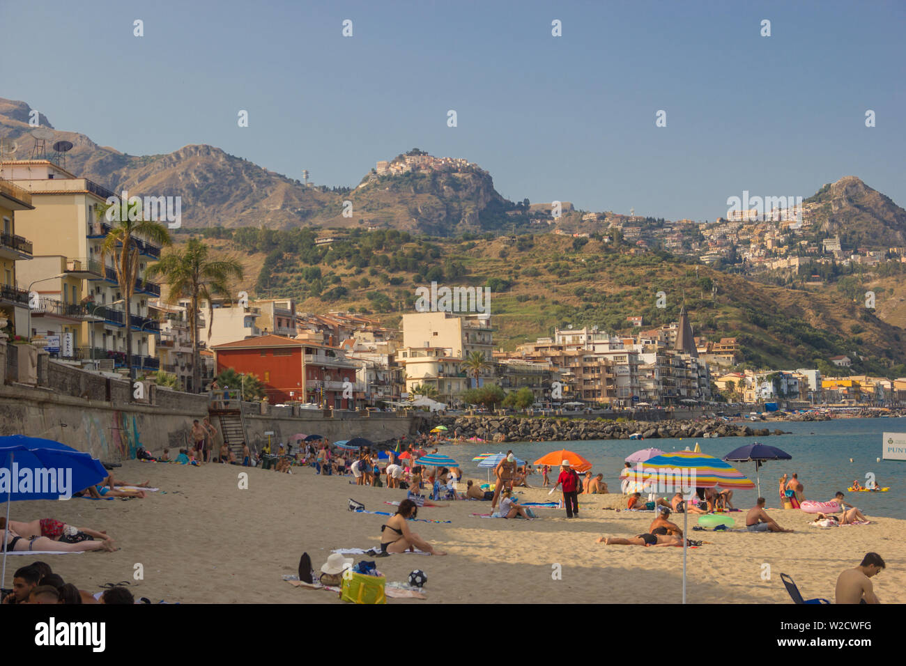 Giardini Naxos Sicily Italy 2019 close up view of the beach life in Summer and buildings of the town along the coast Stock Photo
