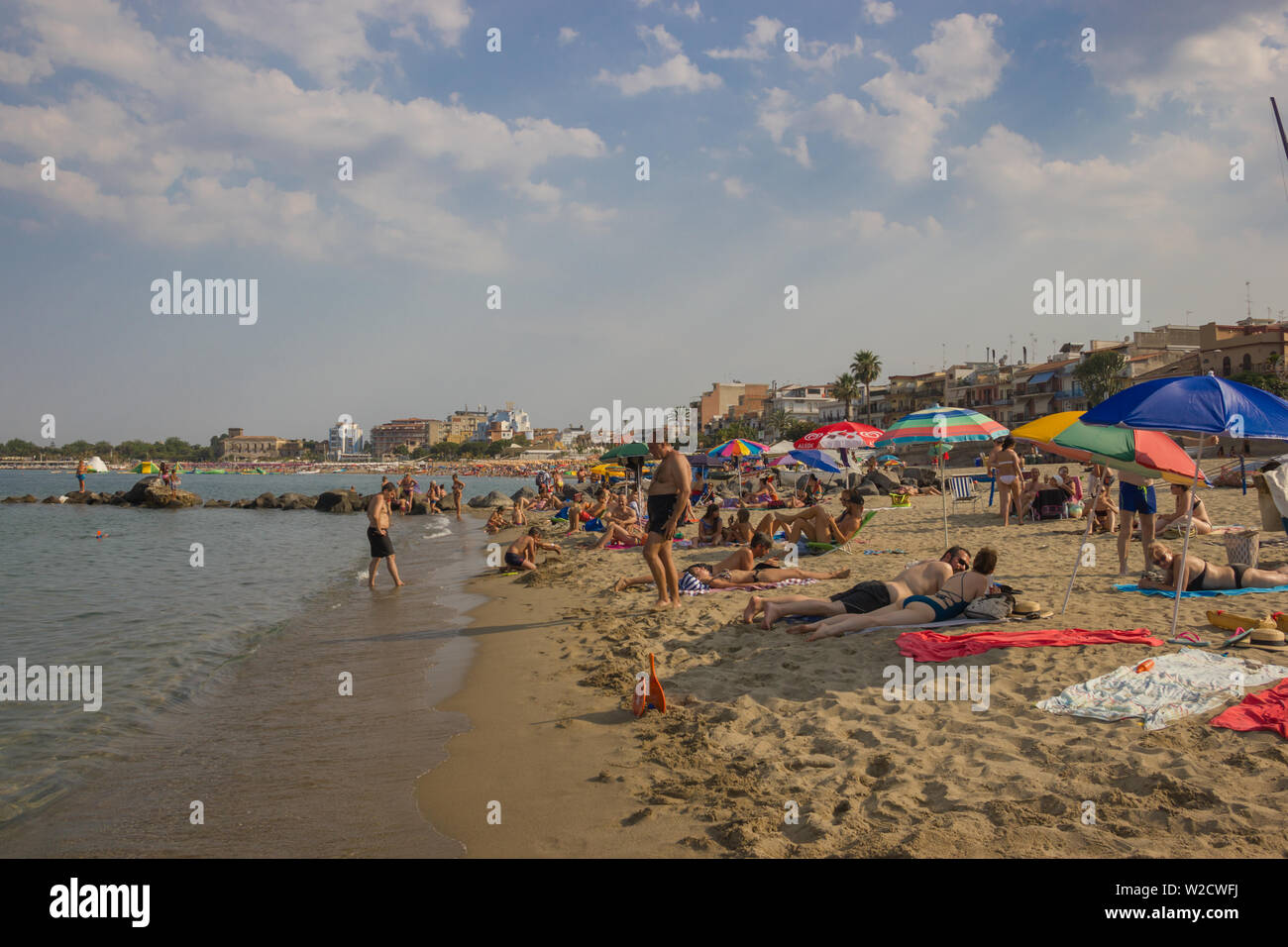 Giardini Naxos Sicily Italy 2019 close view of the people enjoying the Summer vacation at beach, long view of the beach along the town Stock Photo