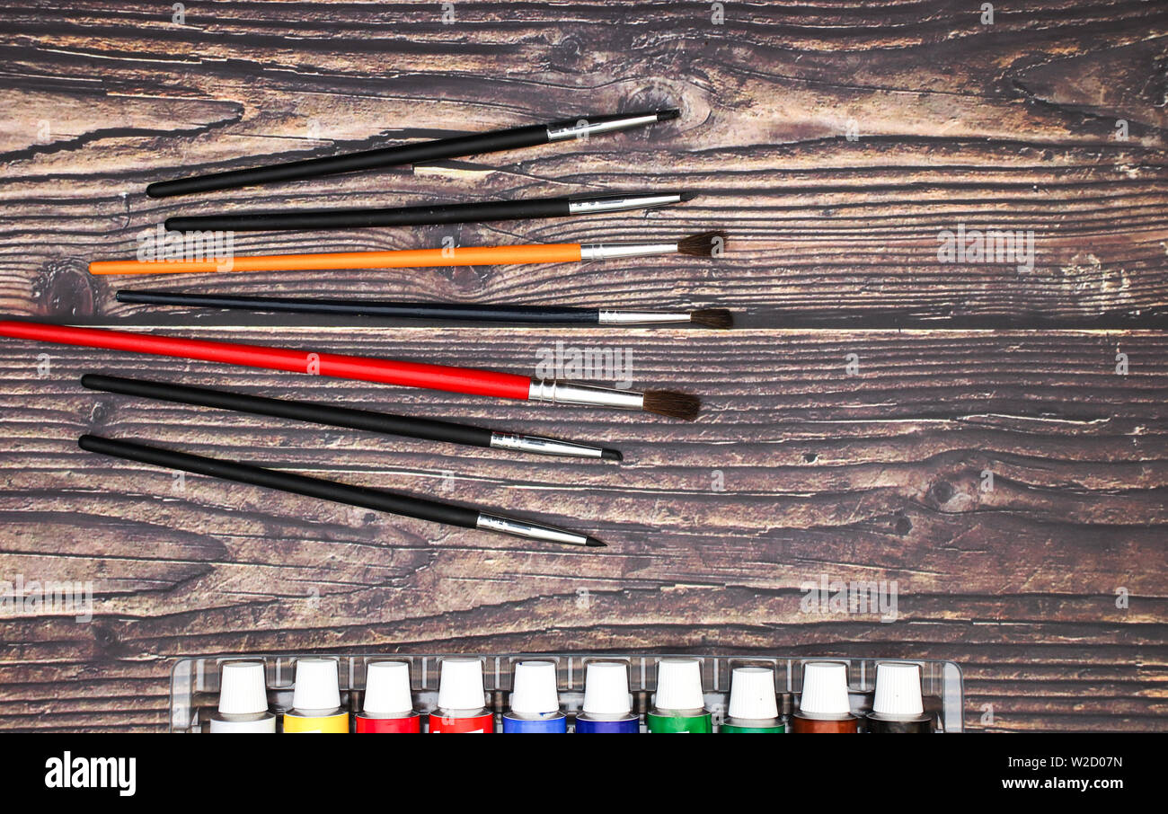 Brushes different size and watercolors on wooden background Stock Photo