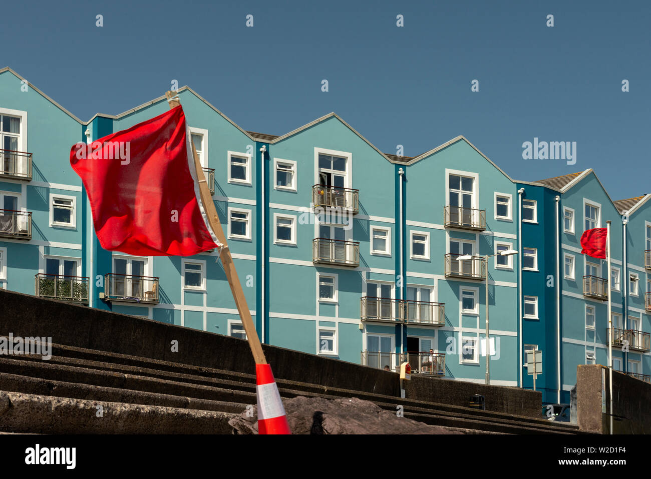 Red flags at the Youghal Strand Promenade and the Strand Palace blue building in Youghal, County Cork, Ireland Stock Photo