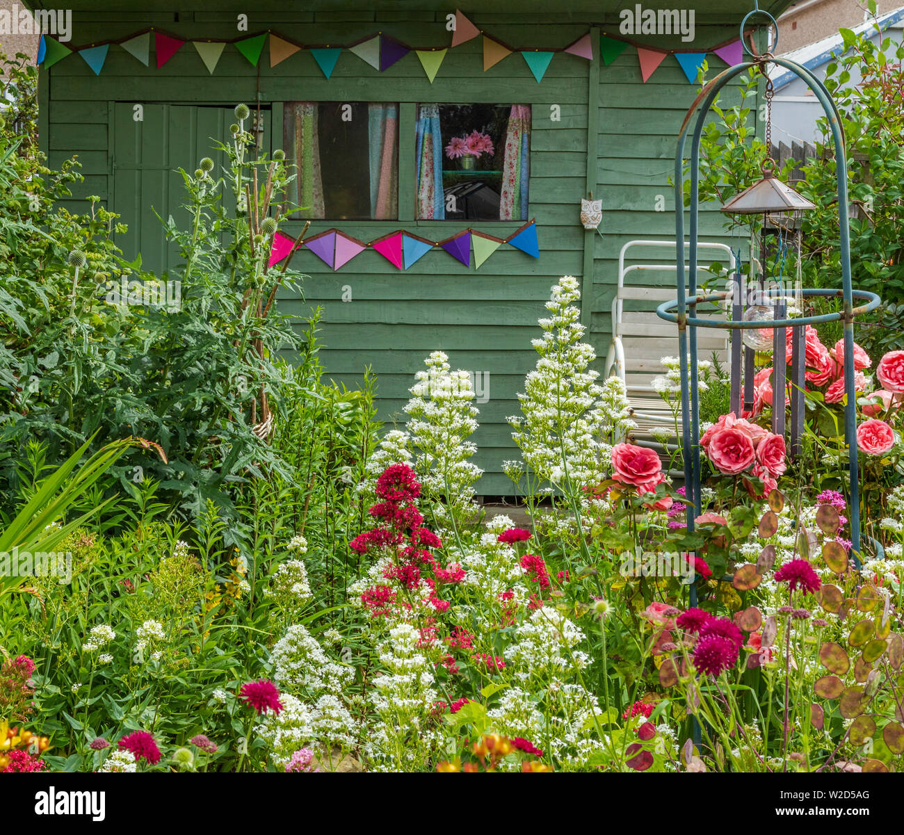 A cottage garden around a wooden shed decorated with bunting. Stock Photo