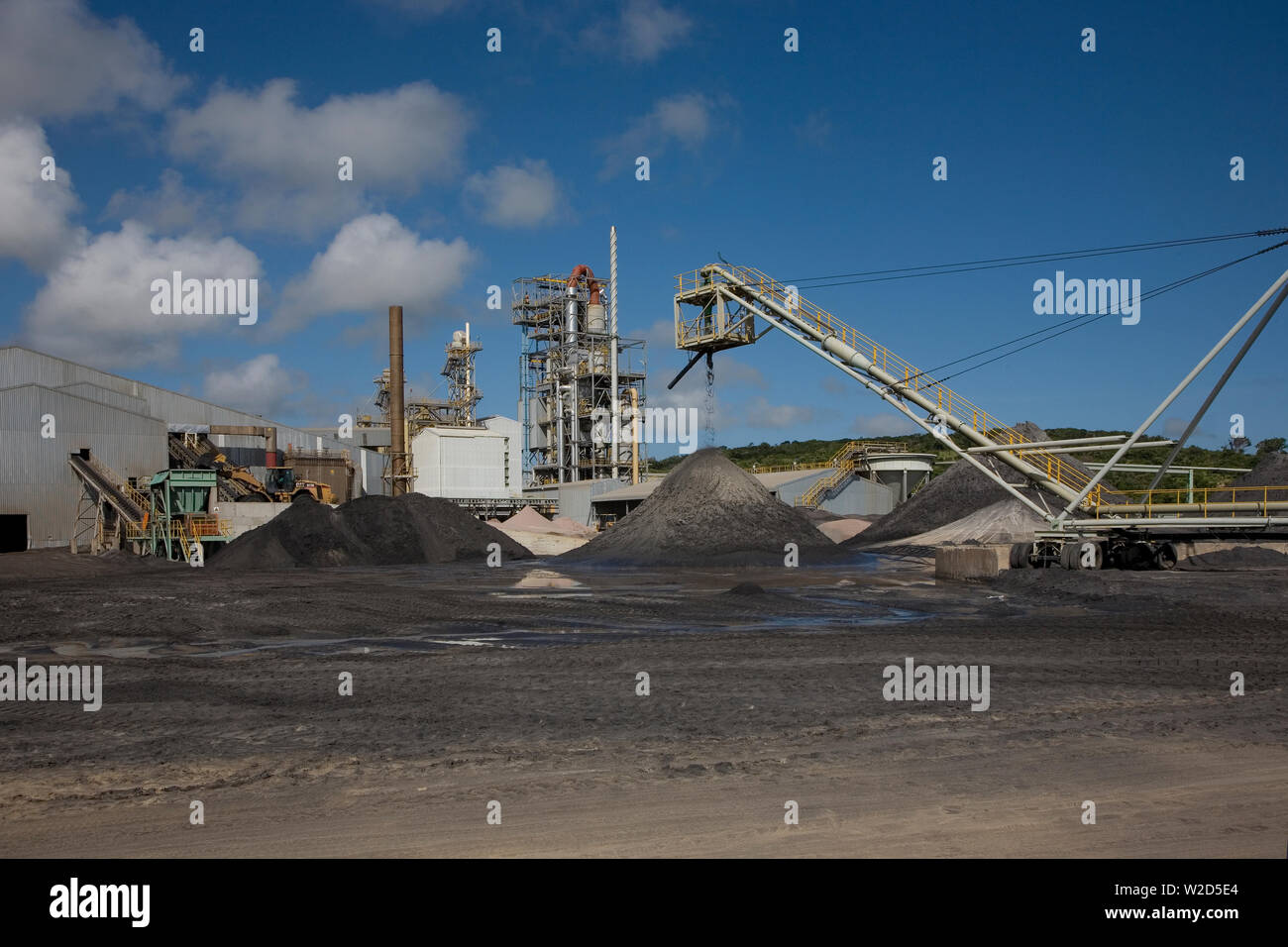 Mining, managing & transporting of titanium mineral sands. Front end loader behind moving heavy mineral sand concentrate from stock pile into hopper Stock Photo
