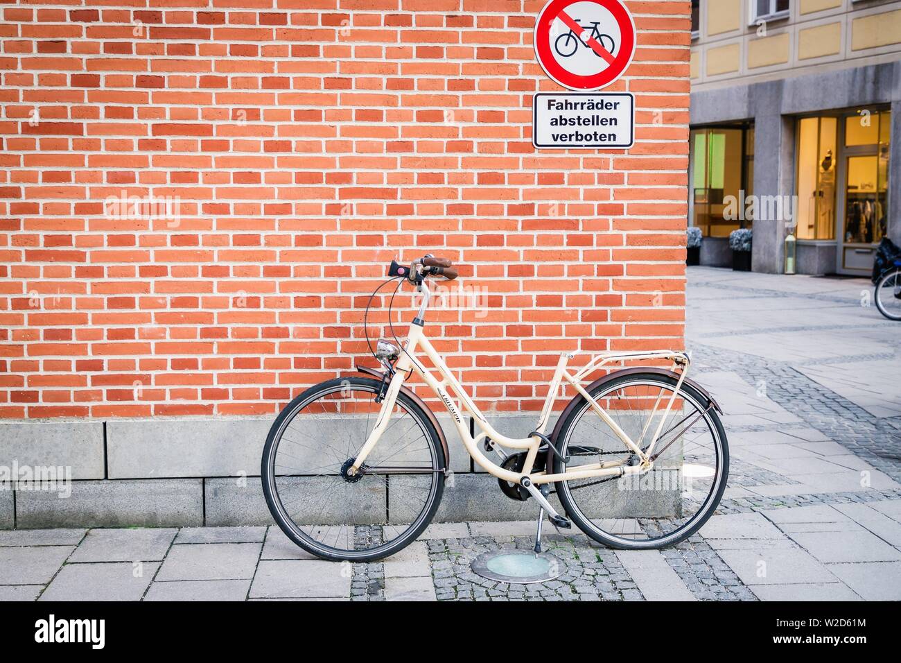Munich, Germany. February 17, 2019. Bicycle on the brick wall background. Inscription in german prohibition sign no parking bicycle. Disobey concept Stock Photo