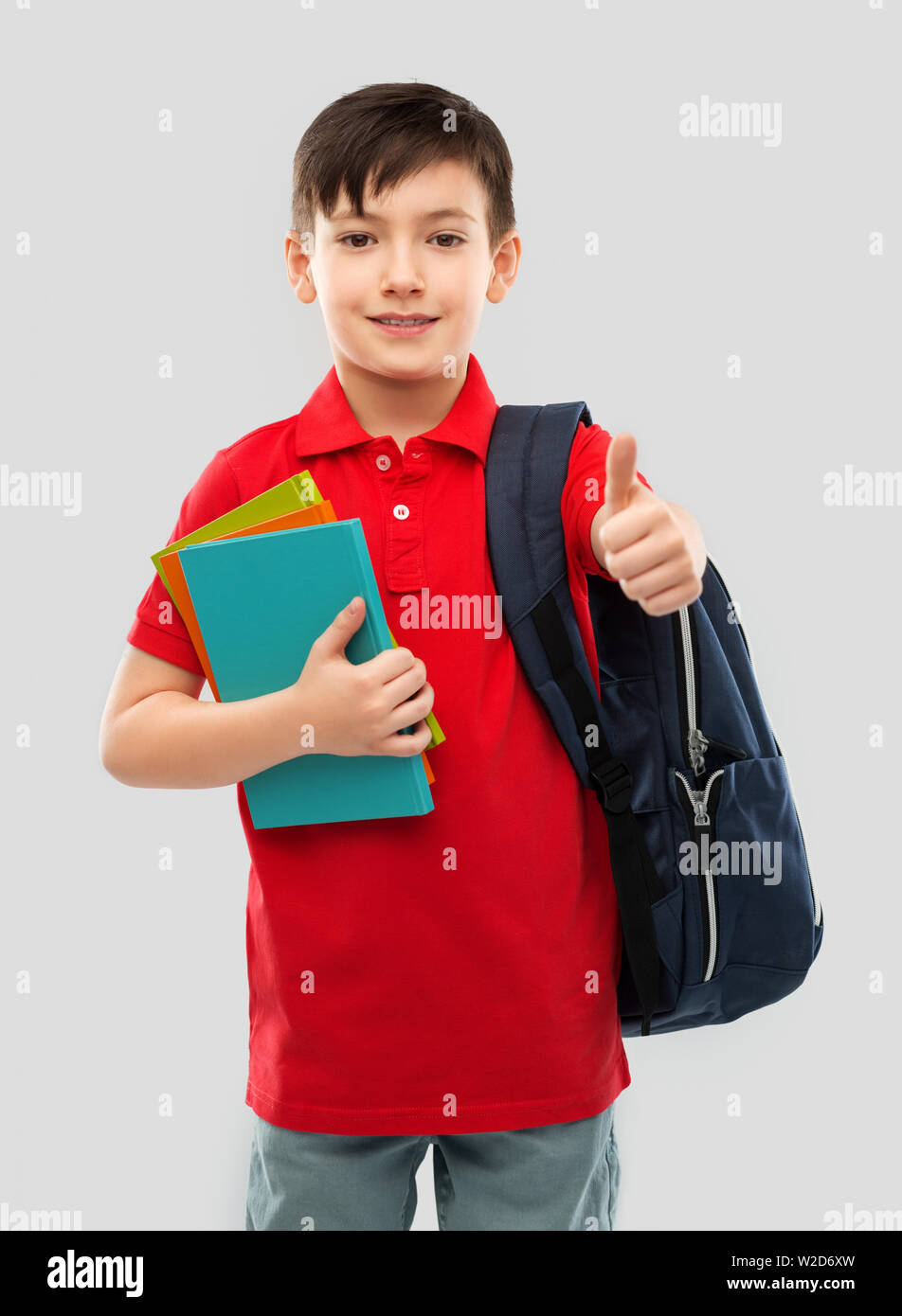 boy with books and school bag showing thumbs up Stock Photo - Alamy