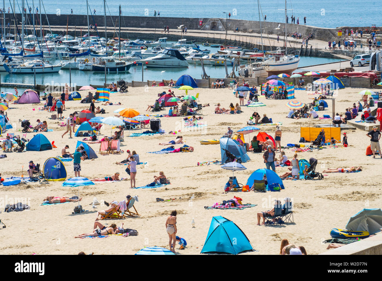Lyme Regis, Dorset, UK. 8th July 2019. UK Weather: Scorching hot sunshine and blue sky at Lyme Regis. Crowds of visitors flock to the sandy beach to enjoy the hot and sunny weather. Credit: Celia McMahon/Alamy Live News. Stock Photo