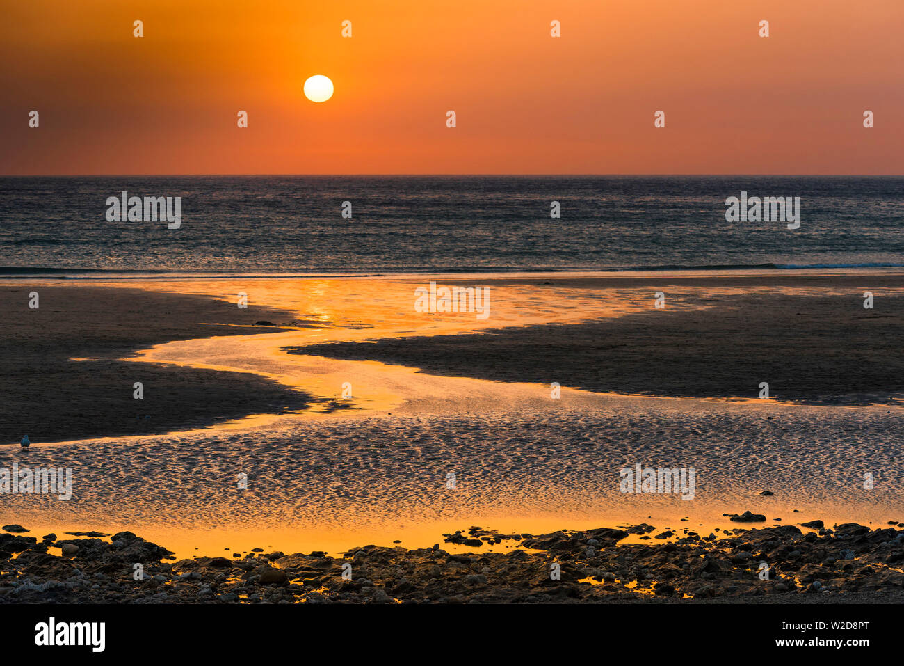 A beautiful intense sunset sets over Fistral Beach in Newquay in Cornwall. Stock Photo