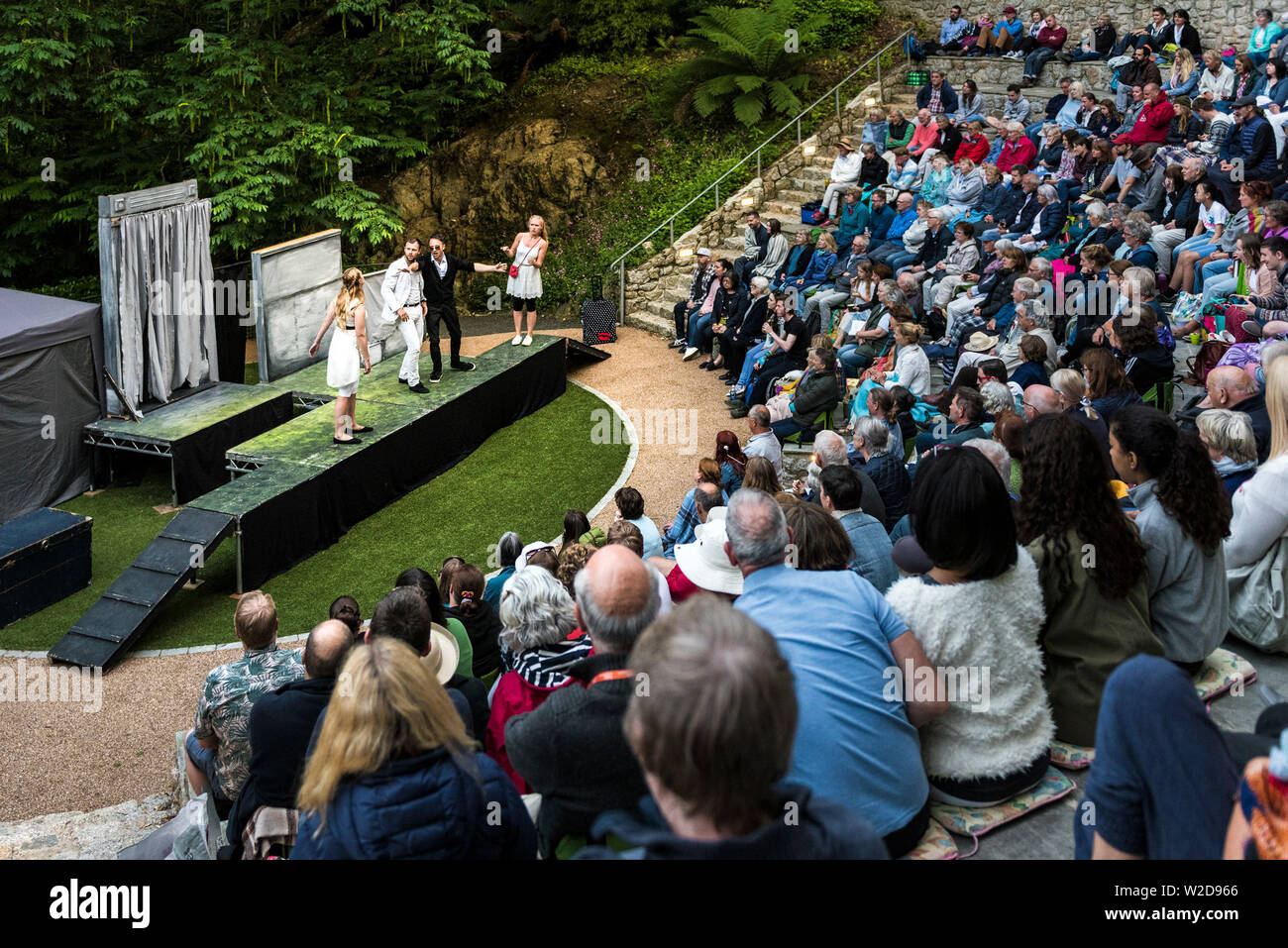 Audience watching actors performing in Shakespeare's  ‘A Midsummer Night’s Dream’ at Trebah Garden Amphitheatre in Cornwall. Stock Photo