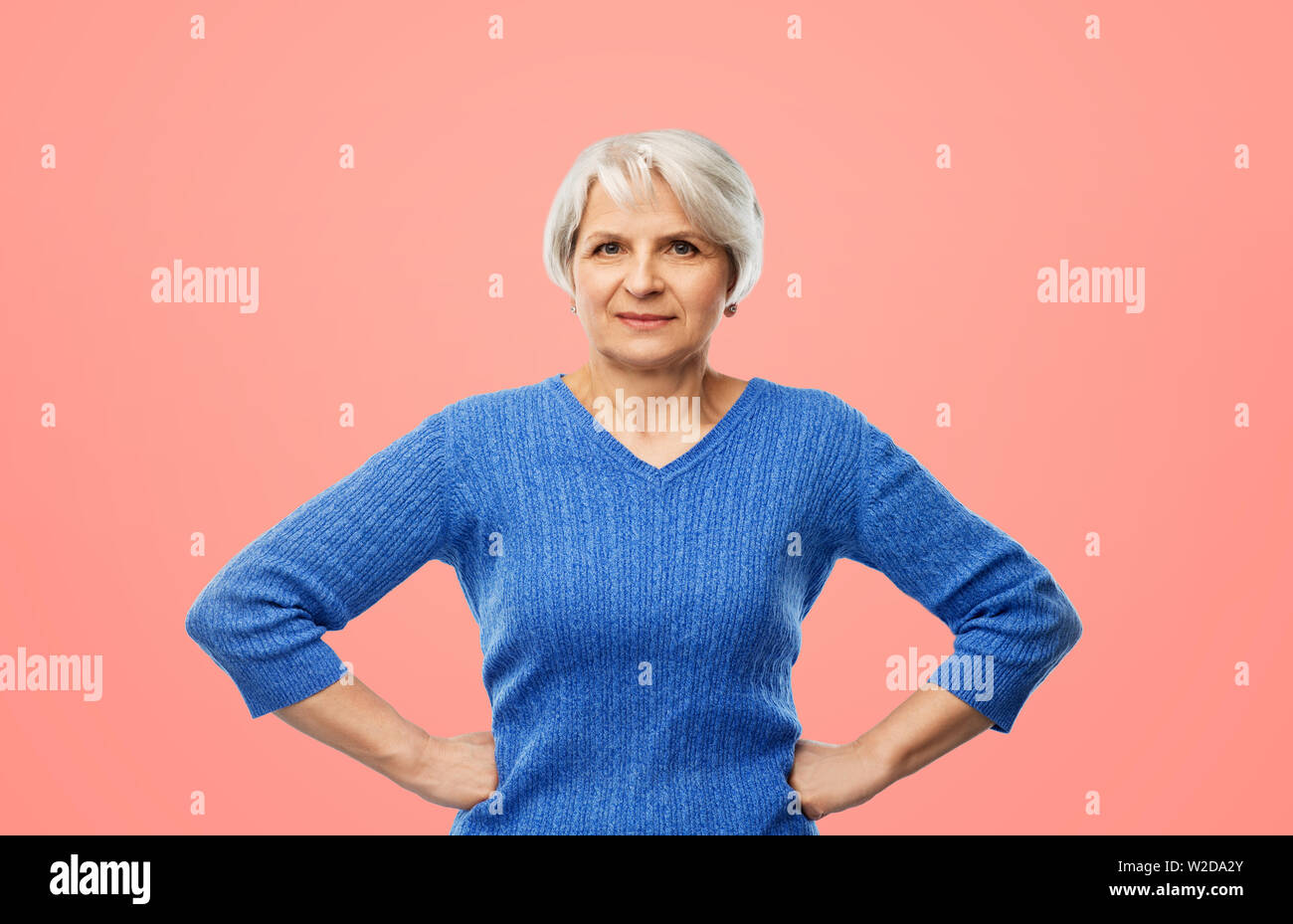 senior woman in blue sweater hands on hips Stock Photo