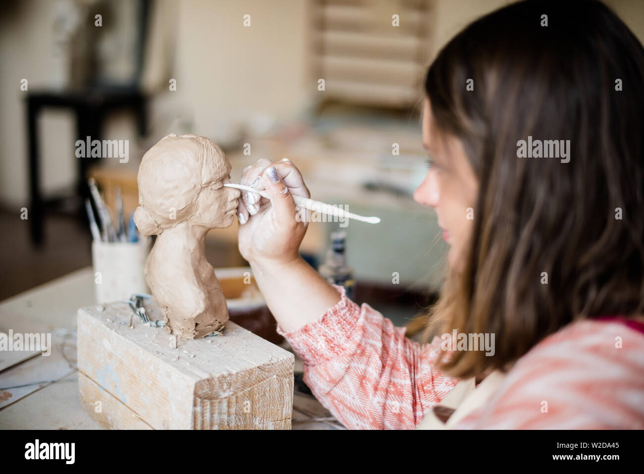 Lady sculptor working in her studio, ceramis artist's hands making objects out of natural clay Stock Photo