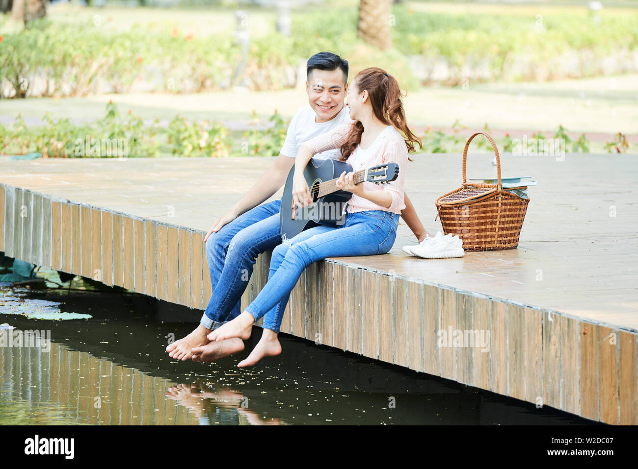 Young happy Asian couple talking to each other while sitting on the ...