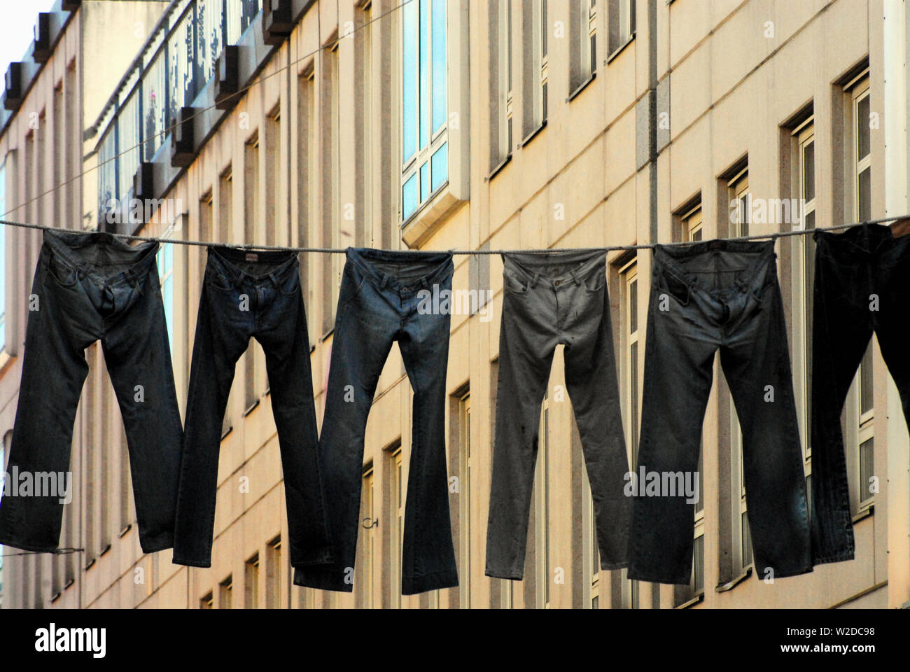 A metaphor for our contemporary lives.  Jeans hanging across a city street in Europe.  Photographed in Sweden. Stock Photo