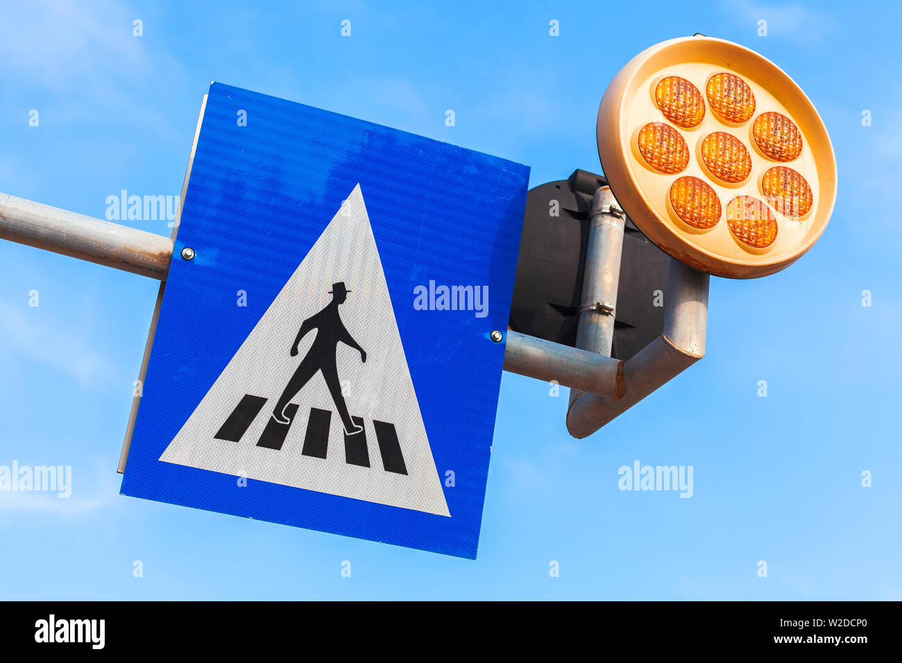 Pedestrian crossing. Road sign and yellow warning lights over blue sky background Stock Photo