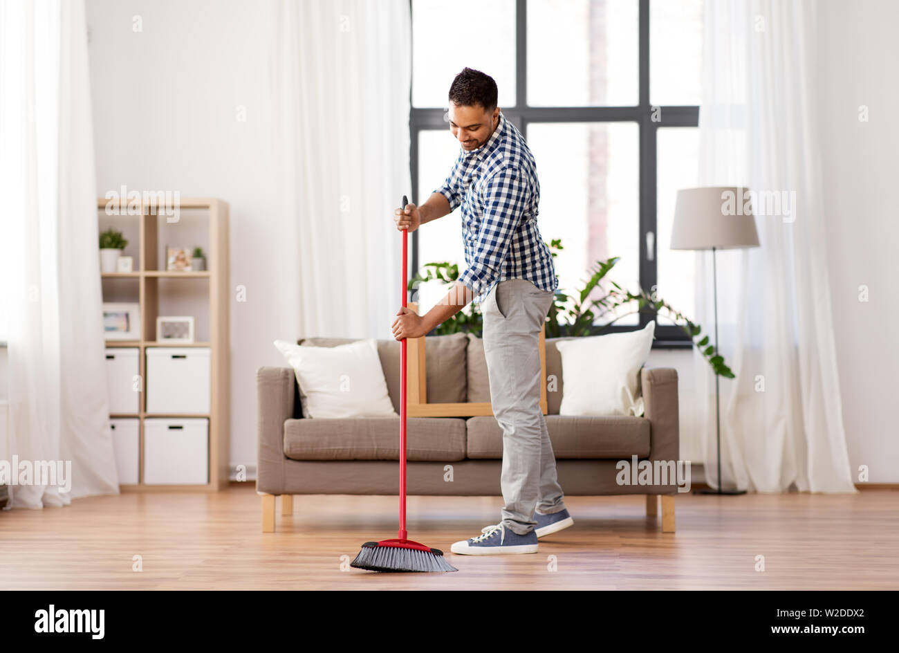 man with broom cleaning floor at home Stock Photo