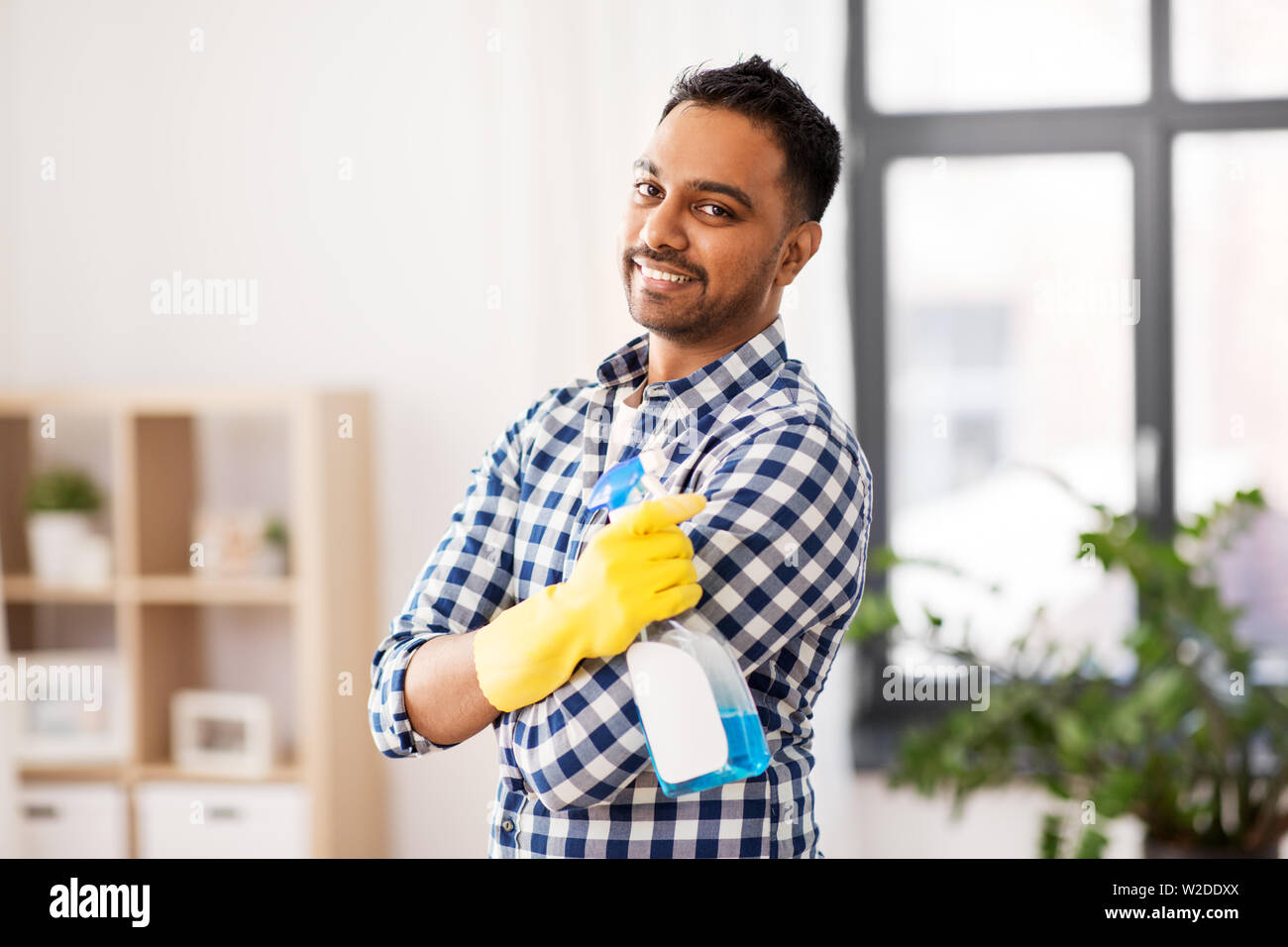 smiling indian man with detergent cleaning at home Stock Photo
