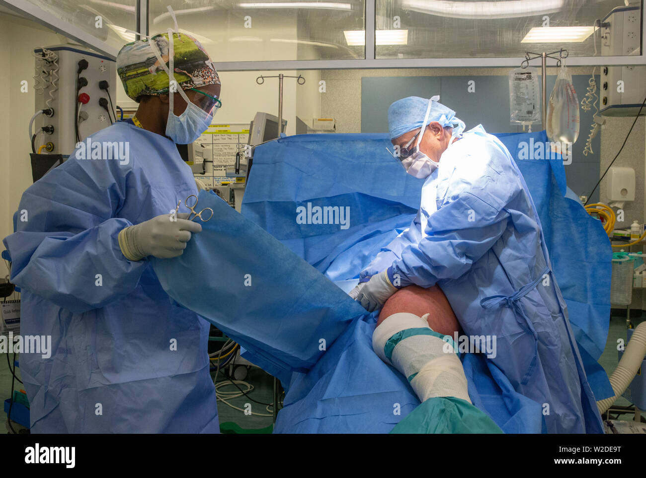 Surgeon And A Nurse Prepare A Patient For A Hip Replacement Operation In An Operating Theatre In