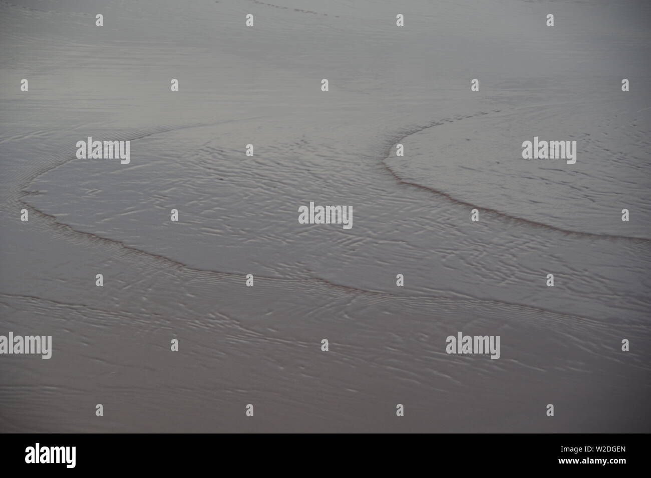 Capillary Waves / Ripples Flowing Over Wet Beach Sand. Natural Abstract ...