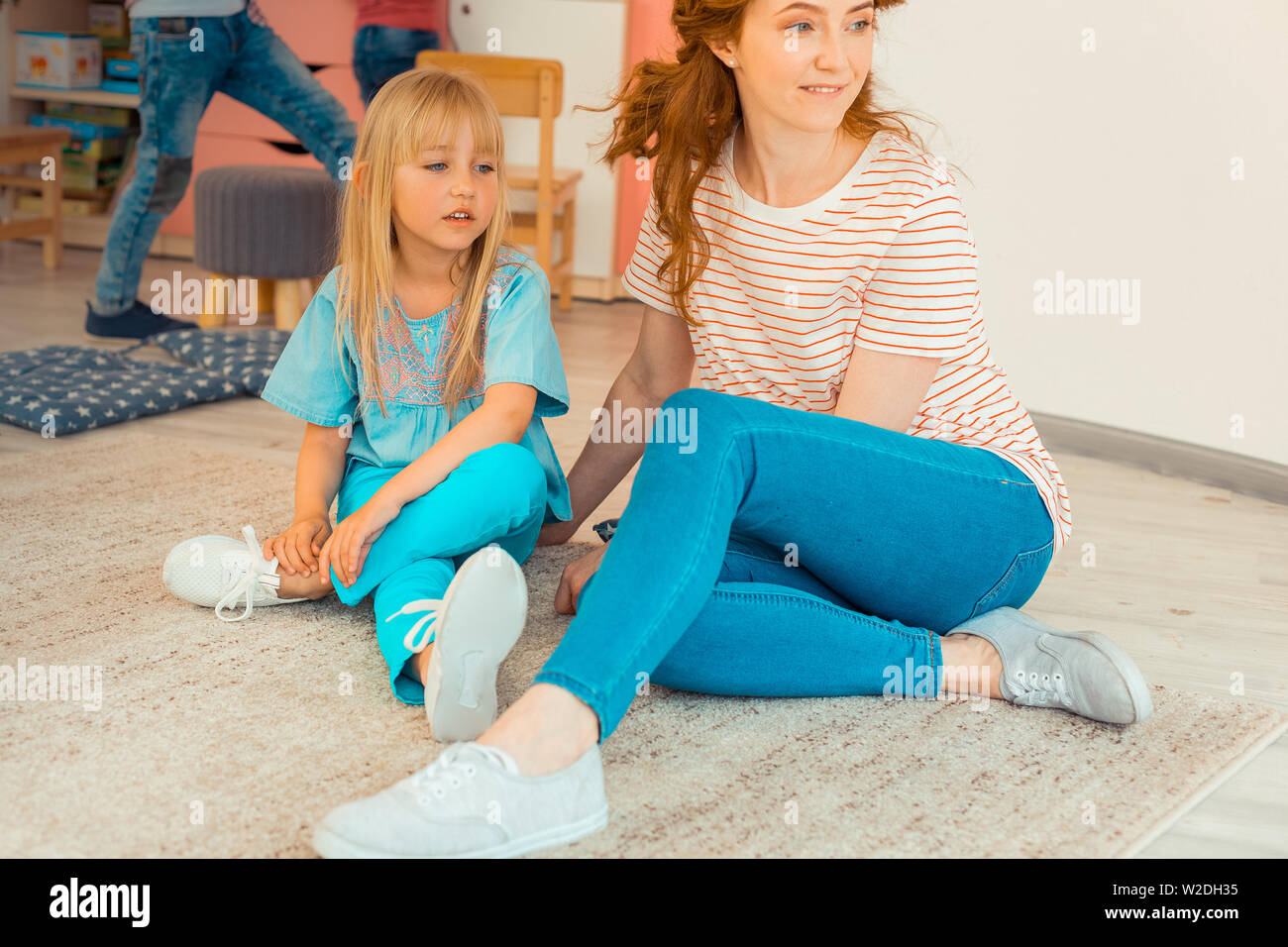 Cute blonde girl sitting on the floor Stock Photo - Alamy