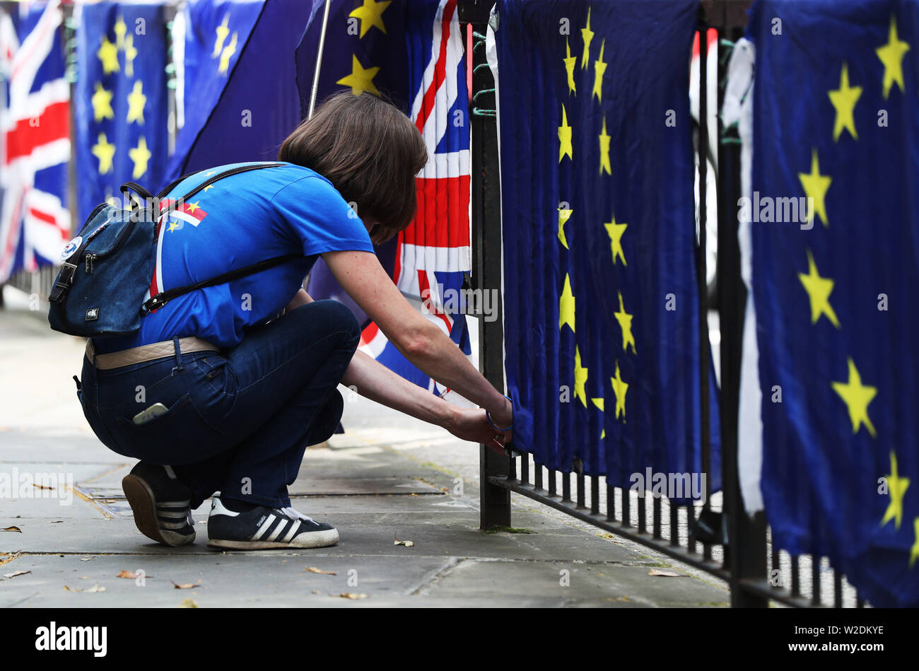 A pro EU activist affixes flags of the European Union and Great Britain together along railings near the Palace of Westminster. Stock Photo