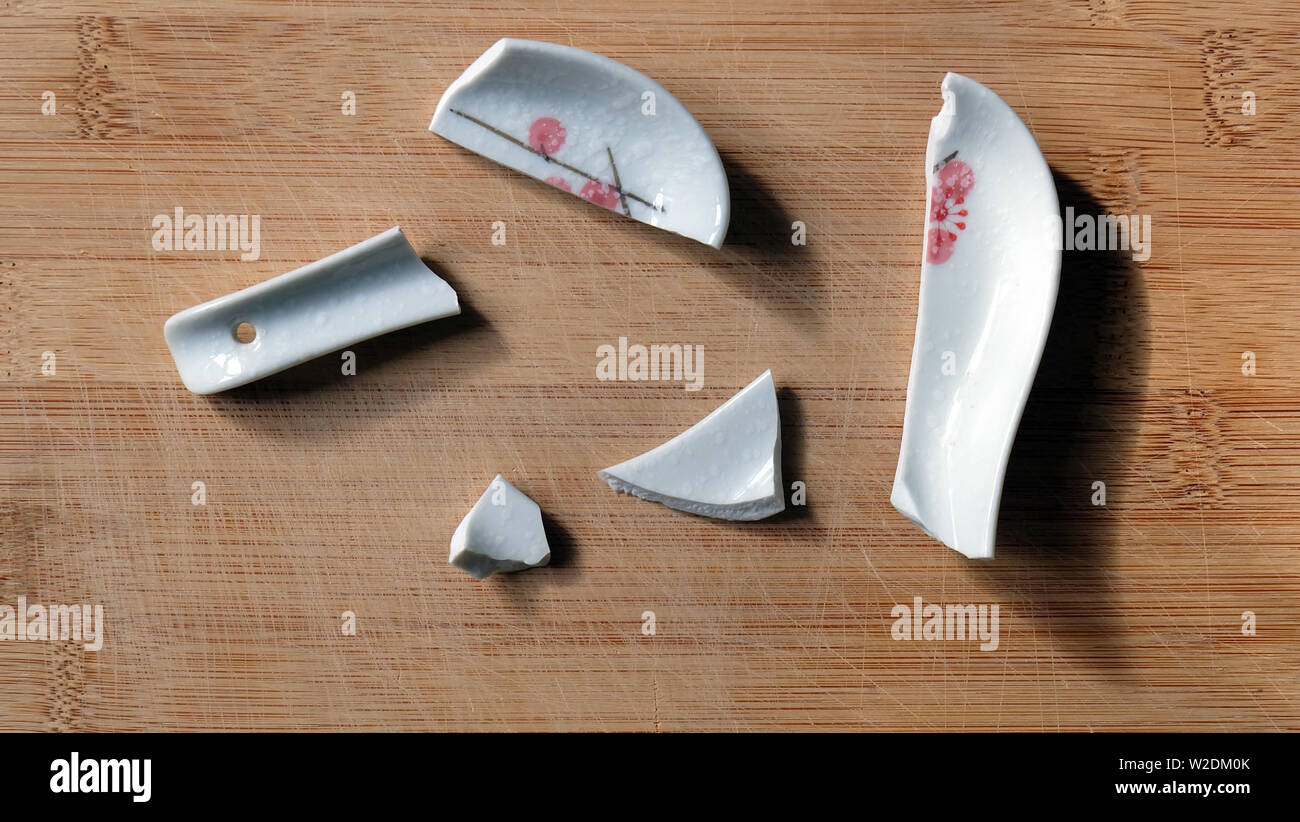 Broken chinese soup spoon with the pieces scattered on a wooden surface. Stock Photo