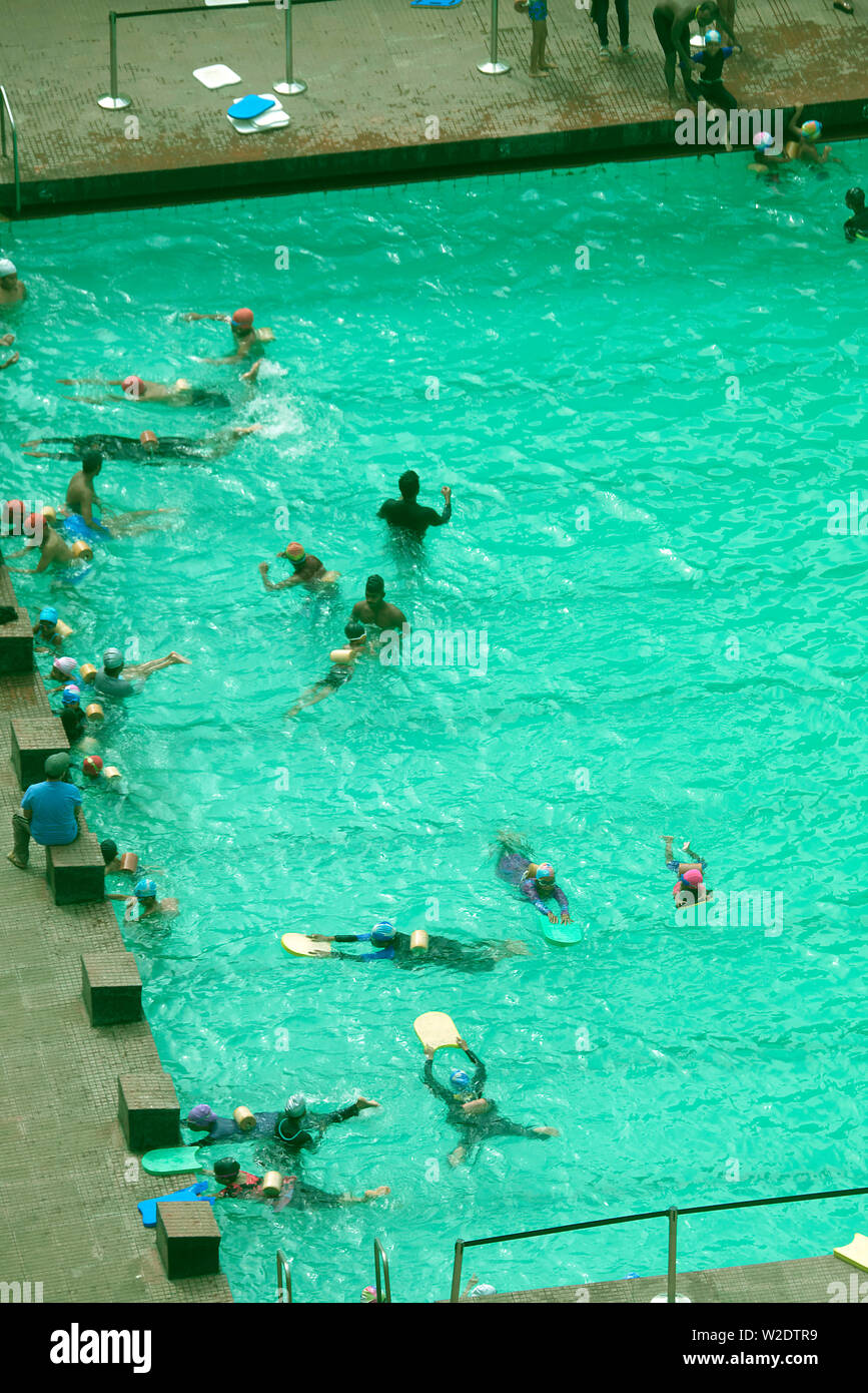 CHILDREN LEARNING TO SWIM IN A PUBLIC SWIMMING POOL IN MUMBAI, INDIA