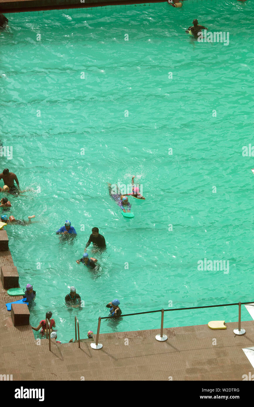 CHILDREN LEARNING TO SWIM IN A PUBLIC SWIMMING POOL IN MUMBAI, INDIA