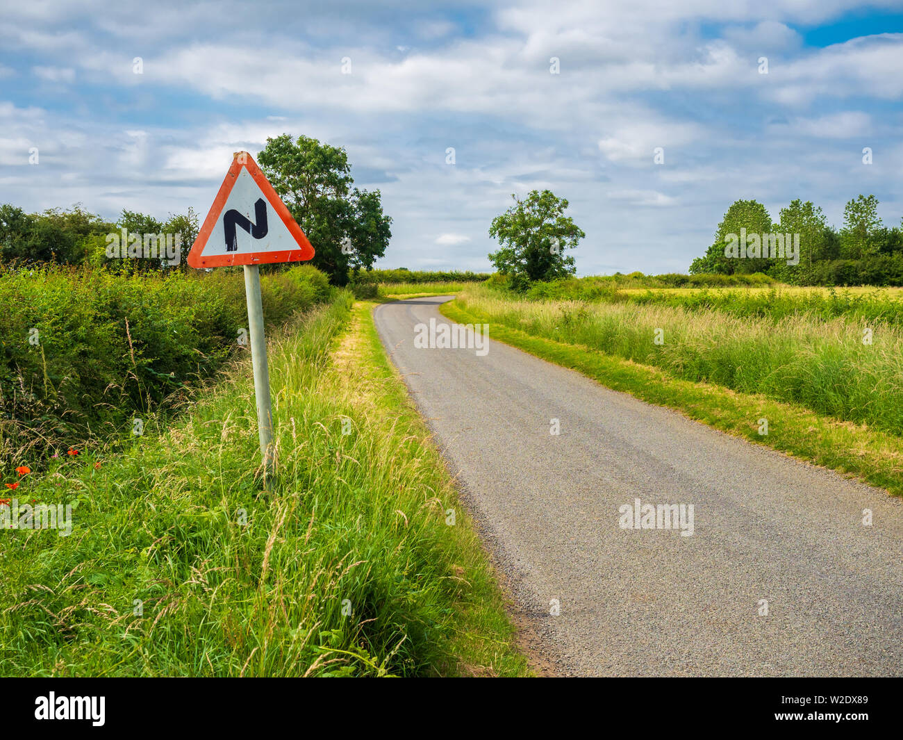 Twisty road ahead zig zag sign at the side of a single track country road Stock Photo