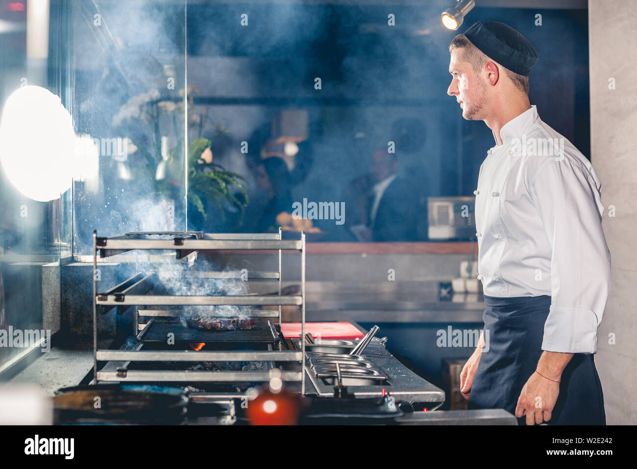 young male cook preparing meal on the grill Stock Photo
