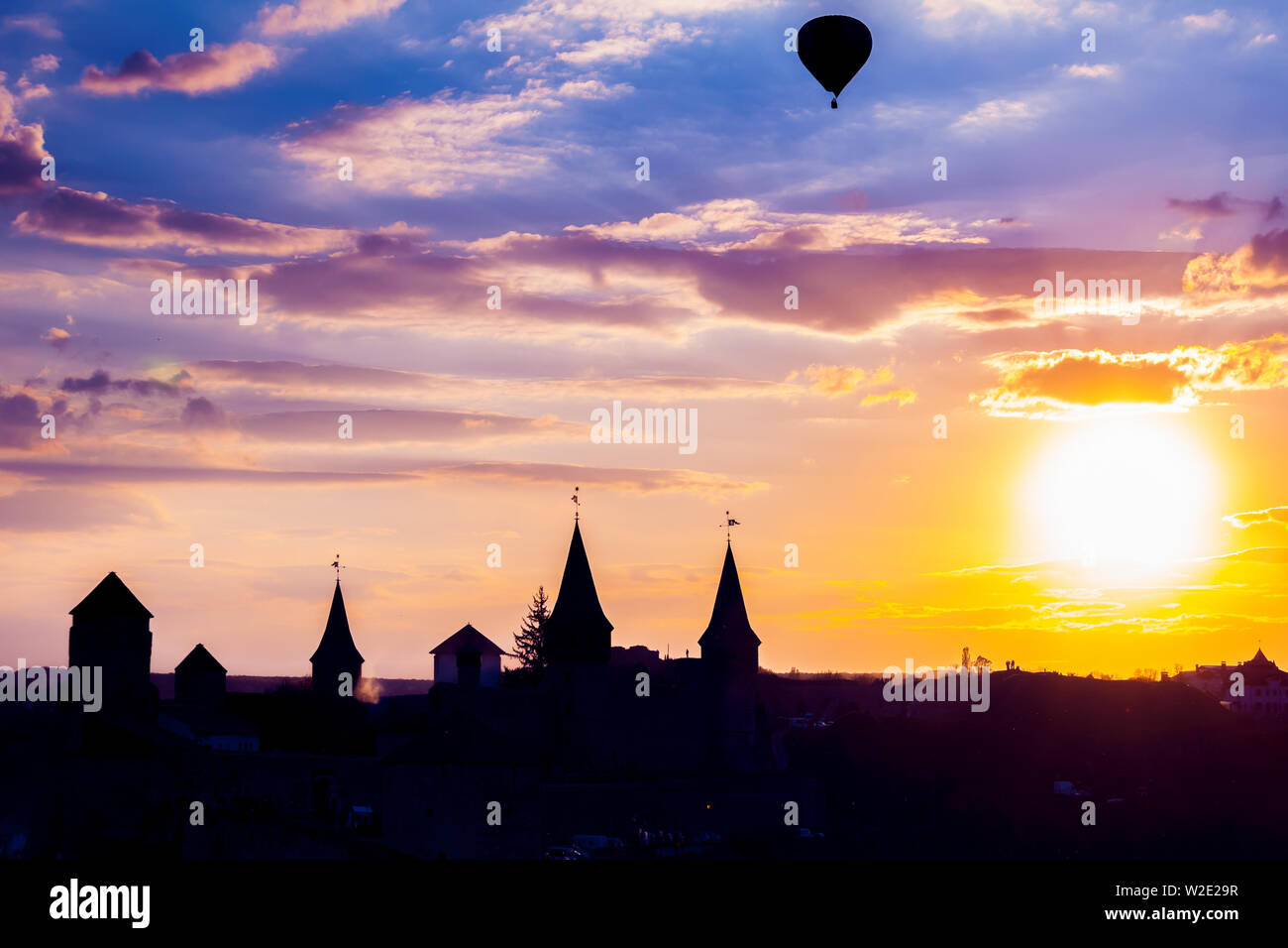 View on the castle in Kamianets Podilskyi and black air balloon during sunset. Ukraine Stock Photo