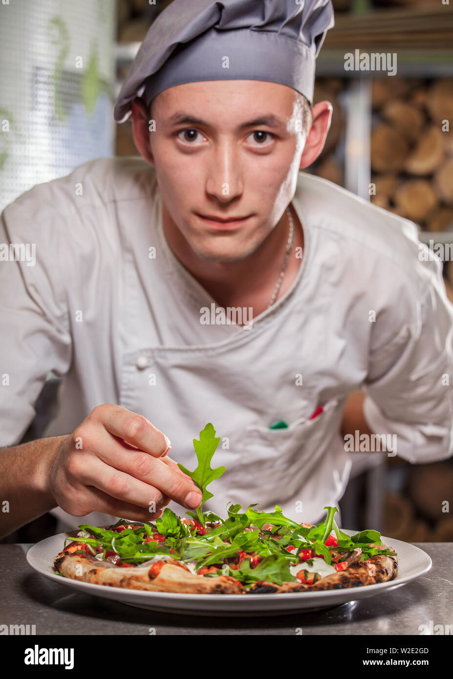 young male cook preparing delicious appetizer with herbs on white plate Stock Photo
