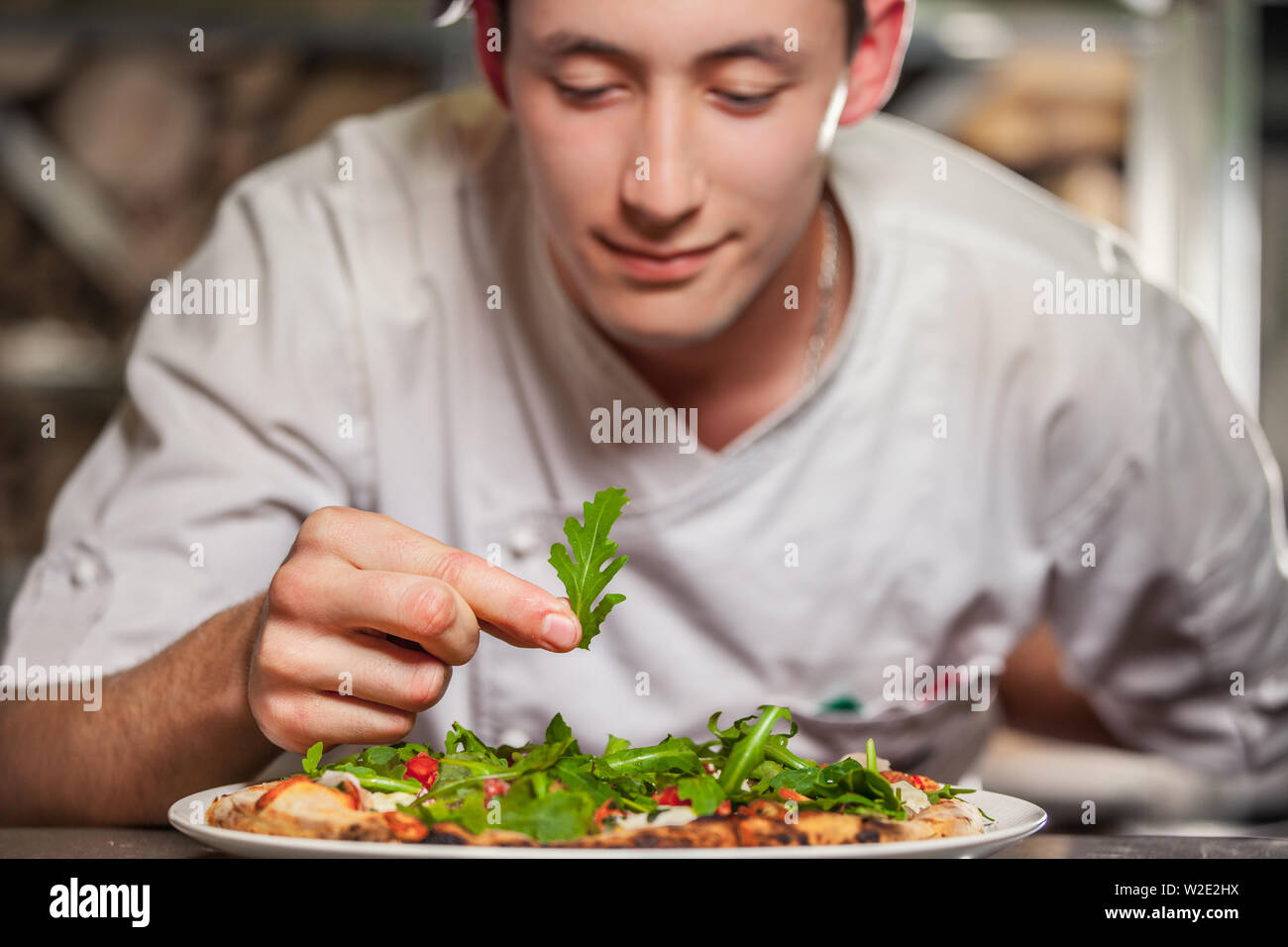young male cook preparing delicious appetizer with herbs on white plate Stock Photo