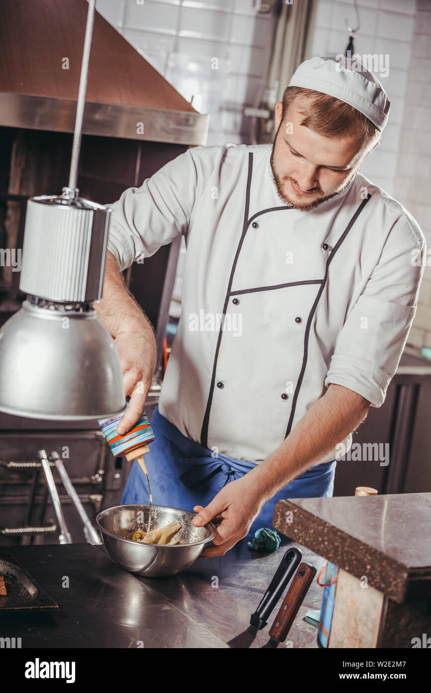 young male cook preparing meal in the restaurant kitchen Stock Photo