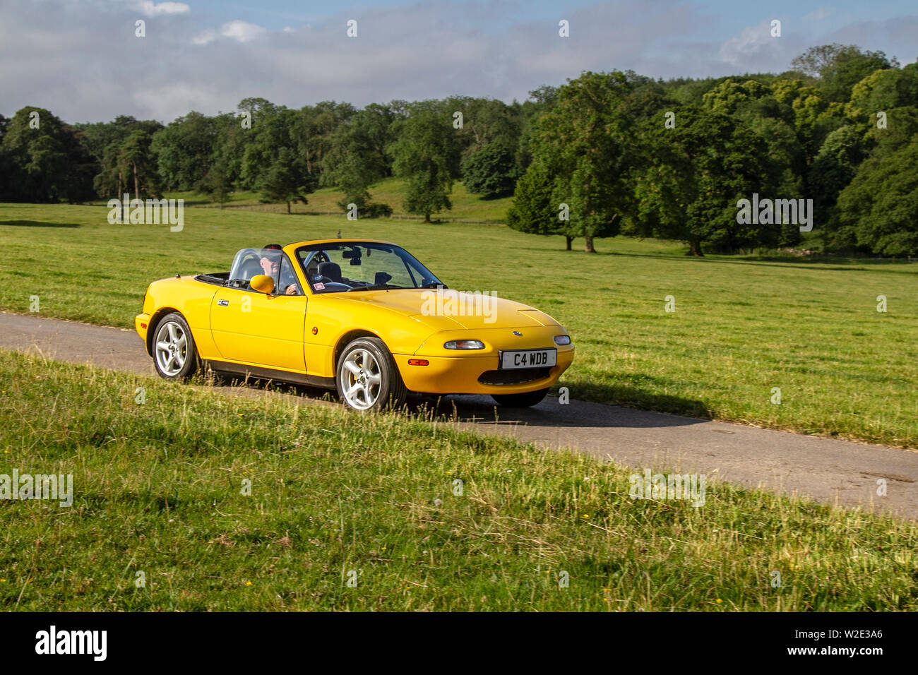 Yellow Mazda Mx-5 California at the Classic Car Rally - Sunday 7th July 2019. Mark Woodward’s midsummer classic car & bike show traveled to scenic Carnforth to showcase more classics, historics, vintage motors and collectibles at this year’s Leighton Hall transport show, an opportunity to see over 500 classic vehicles of yesteryear  at one of the most comprehensive and diverse shows in the summer classic car event. Stock Photo