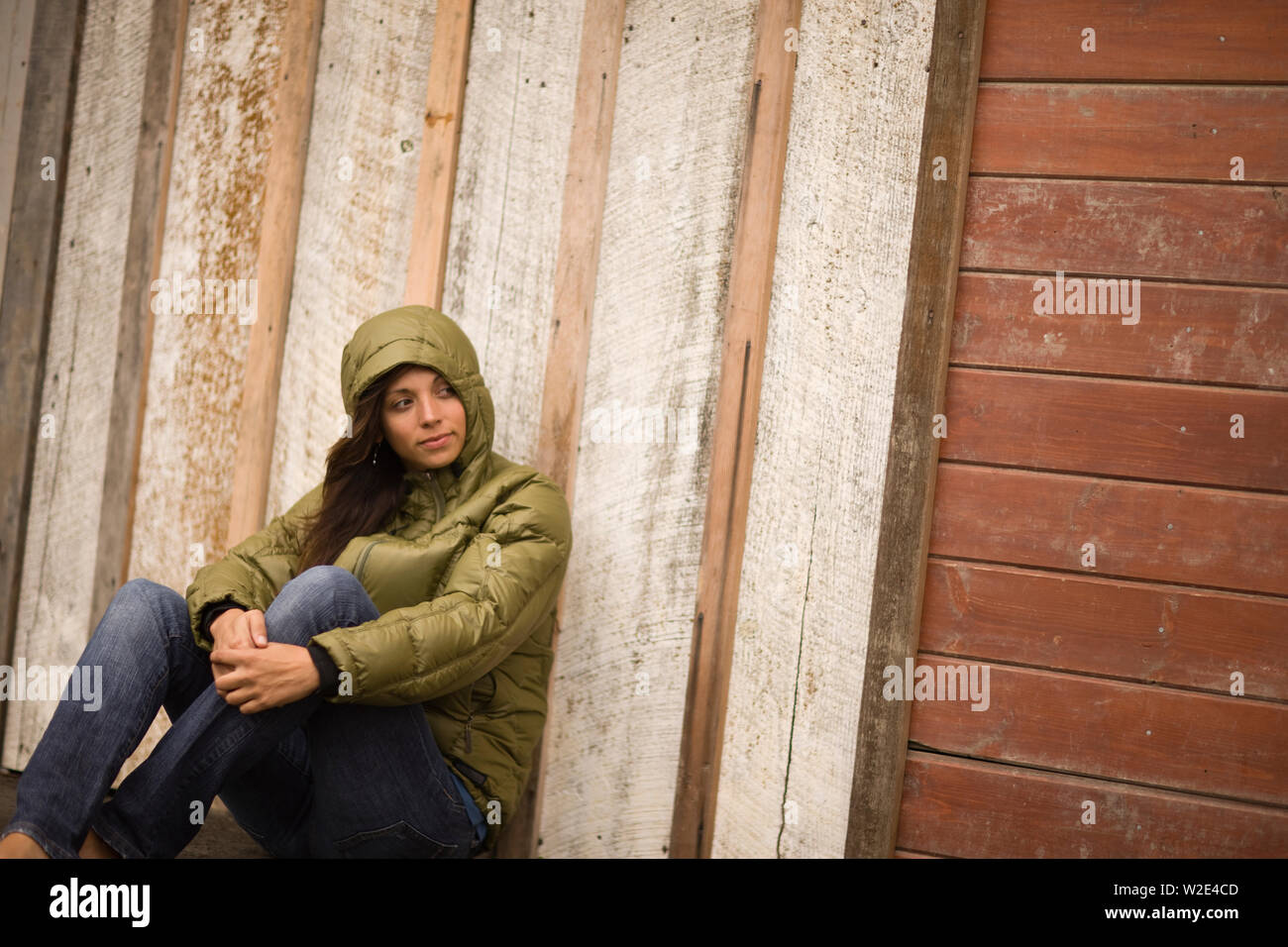Young woman sitting against a wall Stock Photo