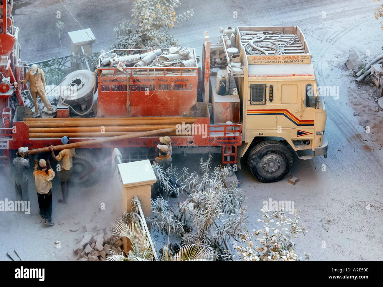 Workers loading/unloading metal pipes to/from a mobile drilling rig, drilling to locate ground water in Hyderabad, India. Stock Photo