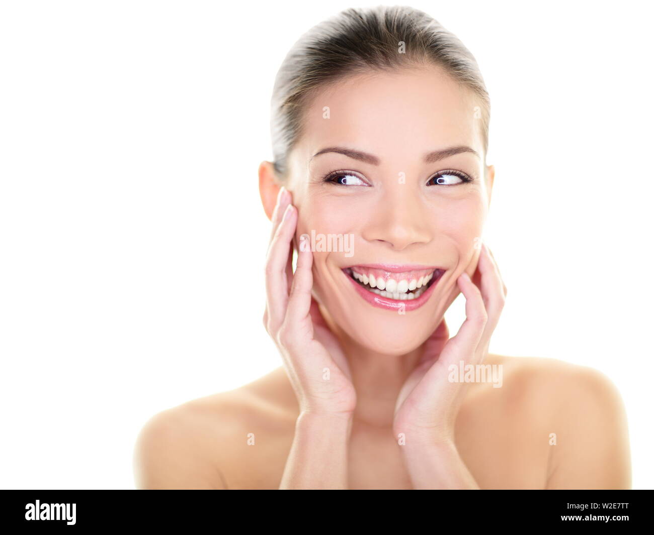 Beauty skin care woman looking at side laughing happy. Skincare asian beautiful woman touching face and perfect skin looking away for body care product advertisement. Multi-ethnic Asian girl fresh. Stock Photo