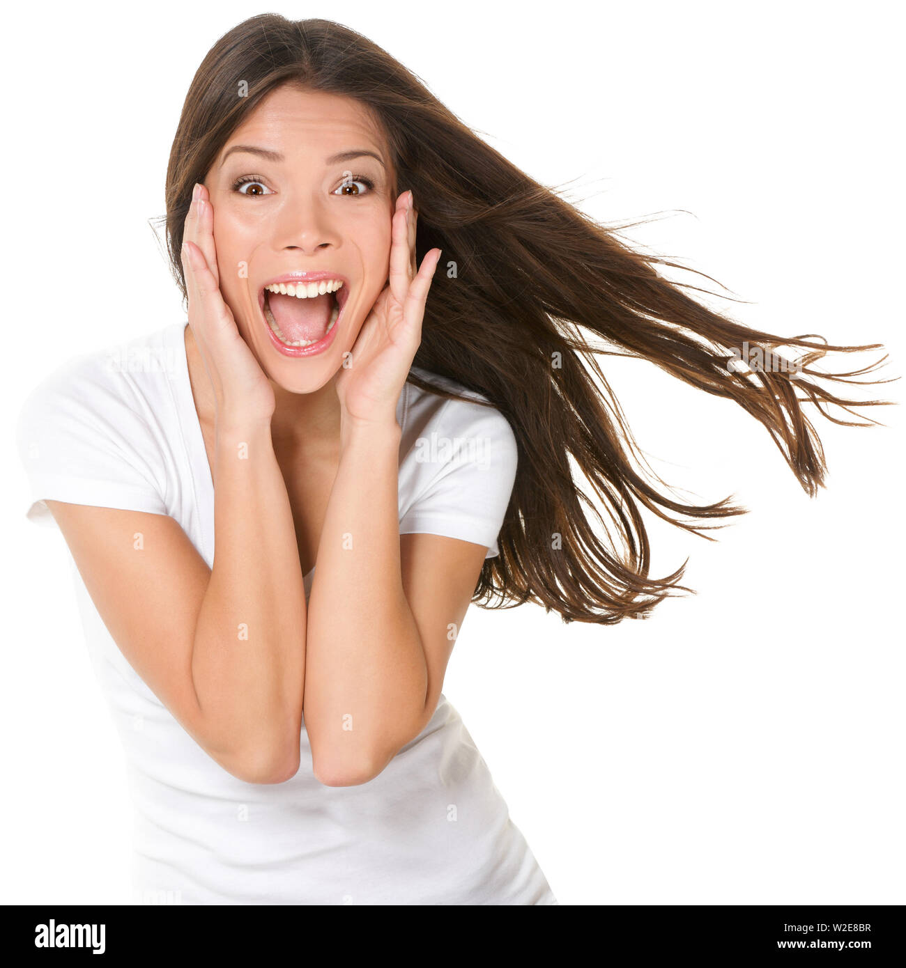 Surprised excited happy screaming woman isolated. Cheerful girl winner shocked over winning with funny joyful face expression. Multiracial Asian Chinese / Caucasian model isolated on white background. Stock Photo
