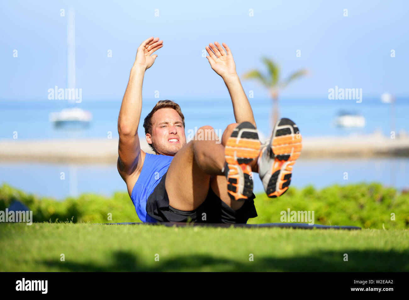 Fitness man doing sit ups exercise for abs outdoors. Fit male