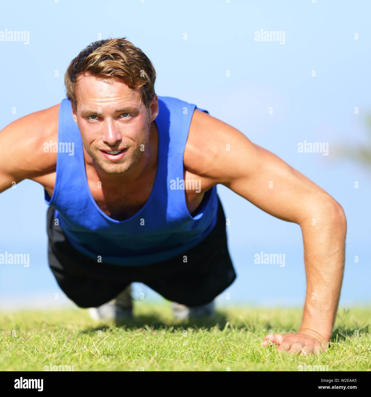 Push ups - fitness man exercising push up outside in grass in summer. Fit male athlete working out cross training outdoor. Caucasian muscular sports model in his 20s. Stock Photo