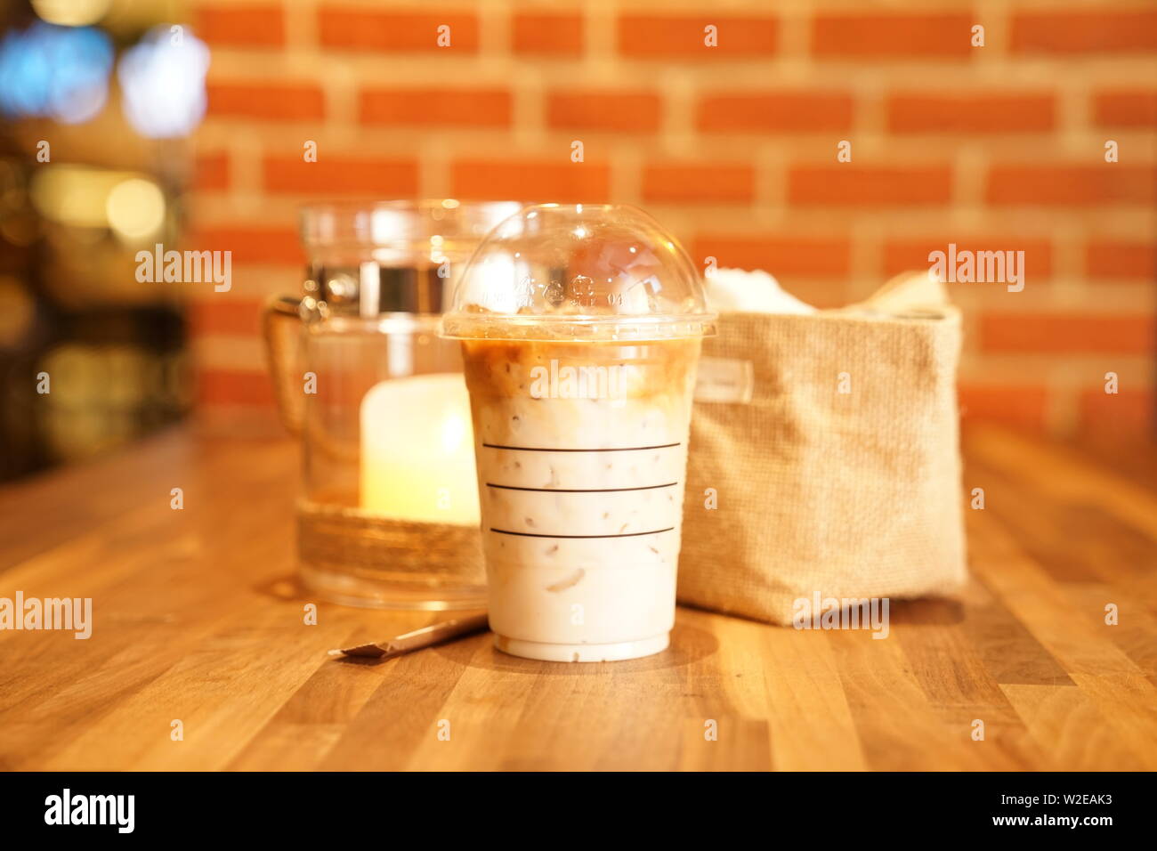 Take away Latte with Brick background on the wood table Stock Photo - Alamy