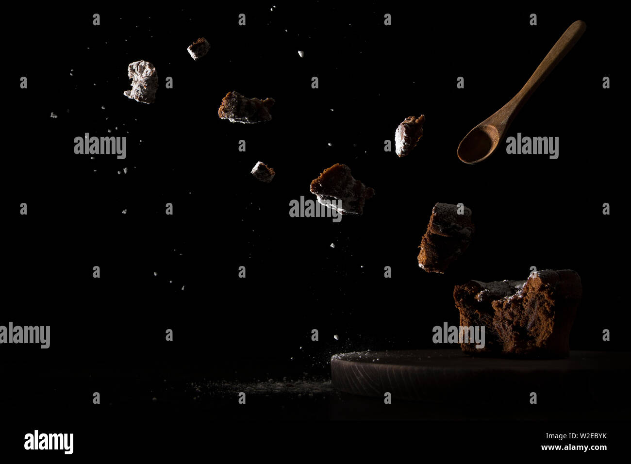 exploding chocolate cake with wooden spoon and dark background Stock Photo