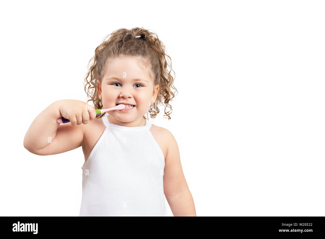 Cute blond girl brushing her teeth on isolated white background Stock Photo