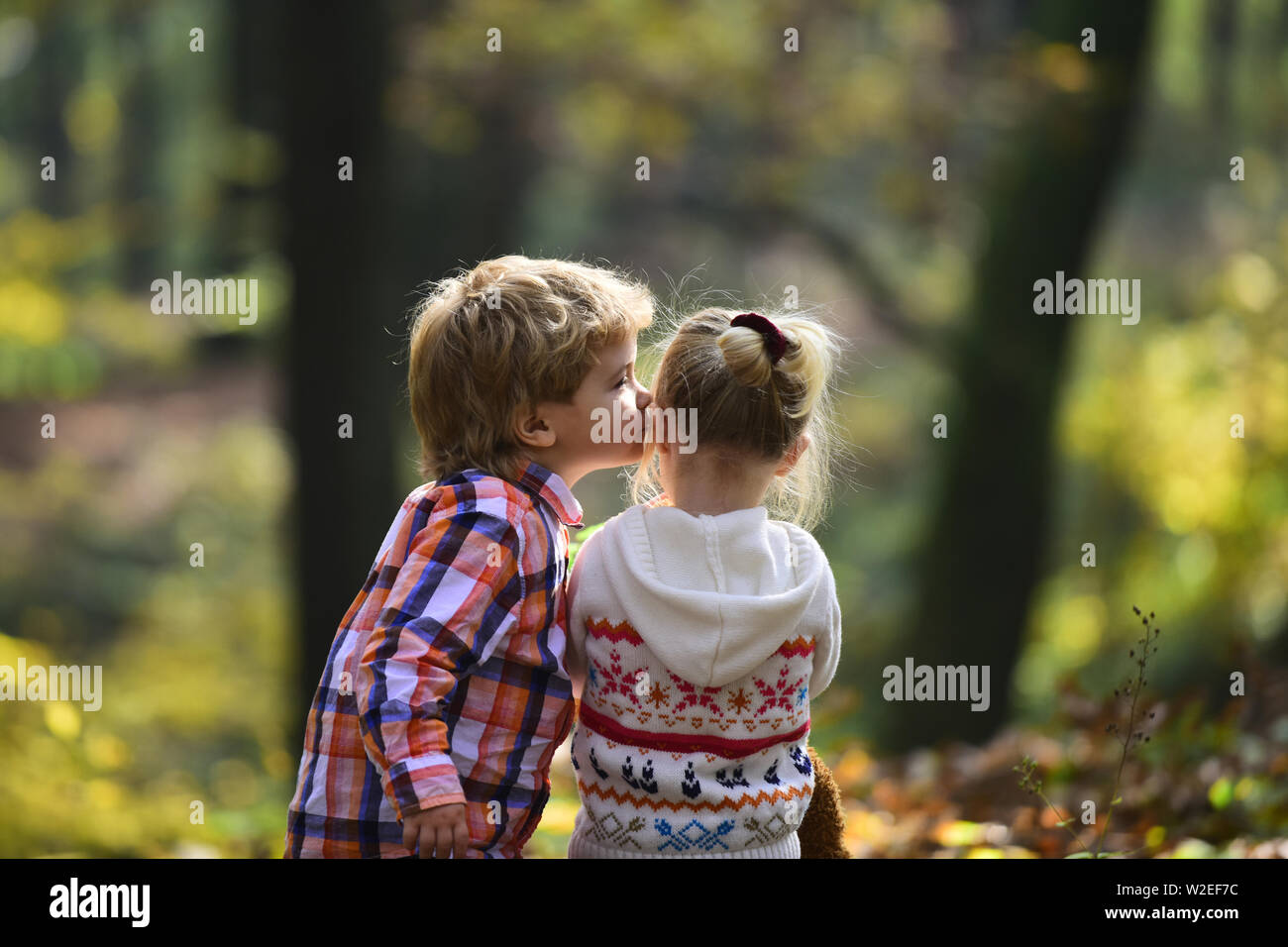 Little boy kiss small girl friend in autumn forest. Brother kiss ...