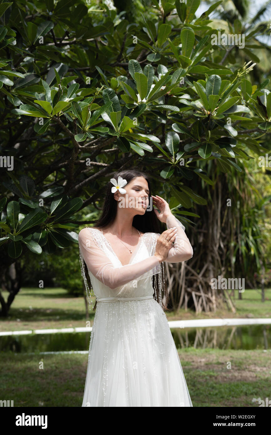 A Bride In A White Dress With An Exotic Flower In Her Hair Is