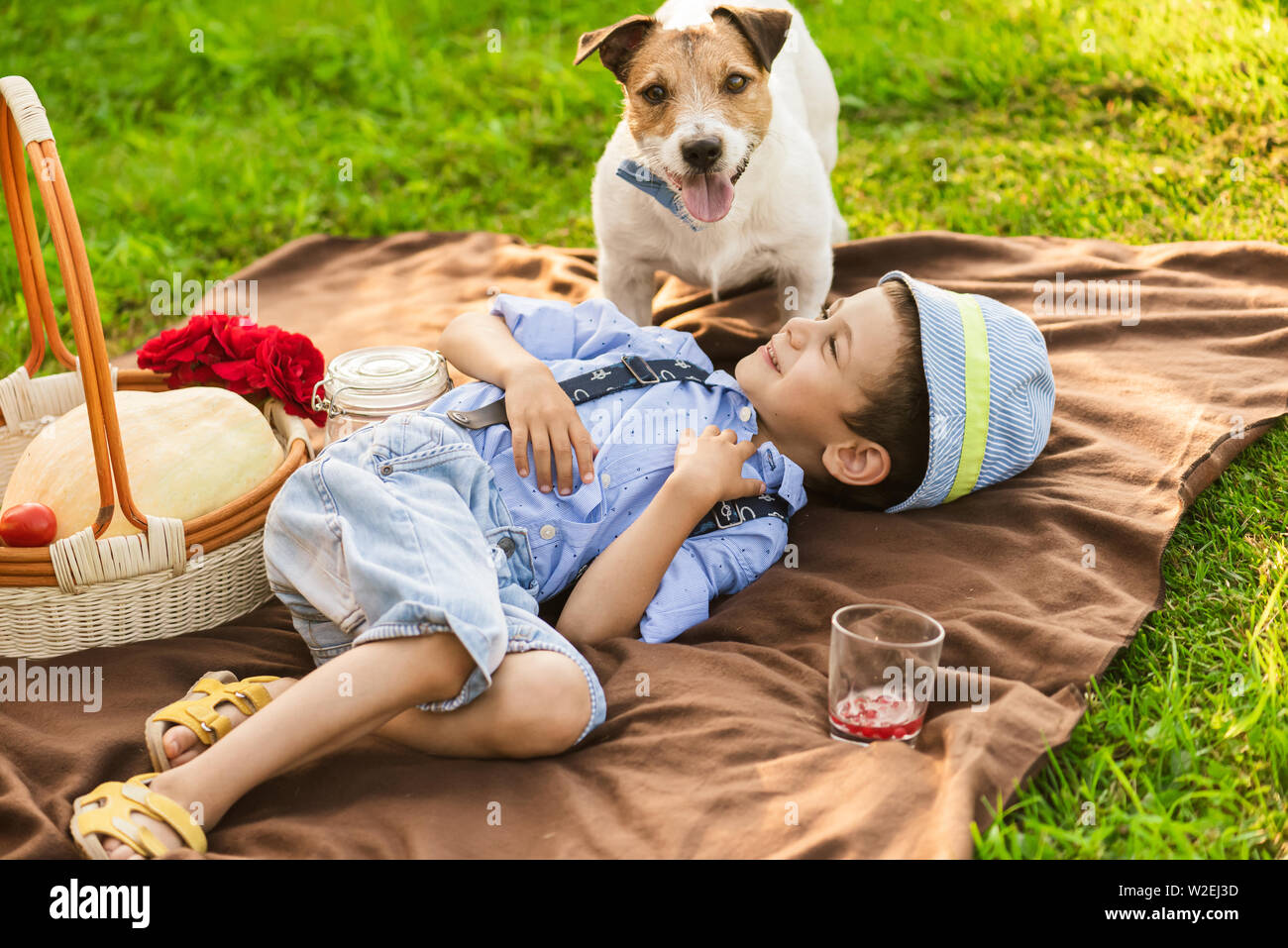 Boy playing with dog at family picnic at green grass lawn Stock Photo