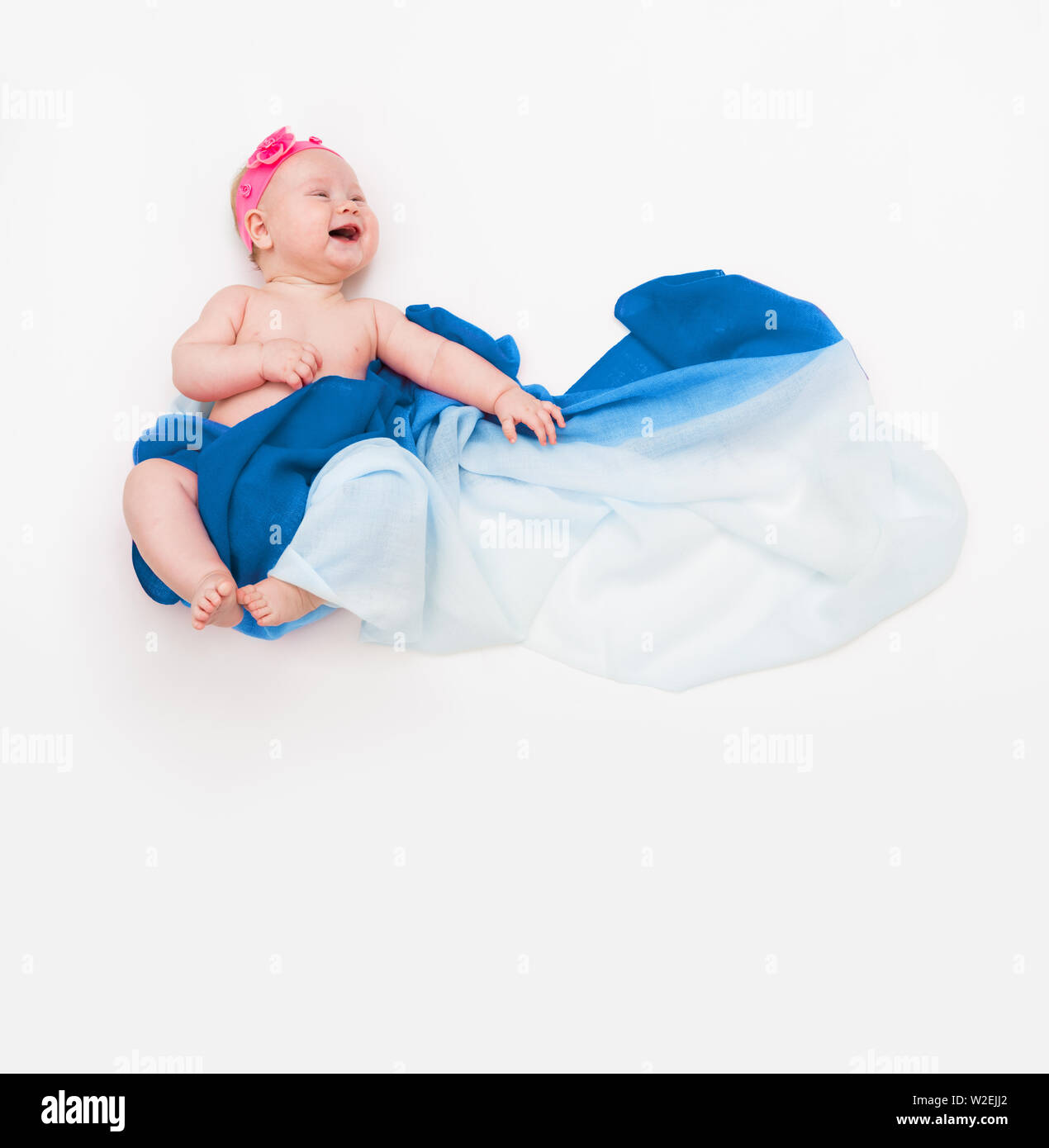 top view of cute infant laughing baby wrapped in a blue scarf depicting a cloud. Stock Photo